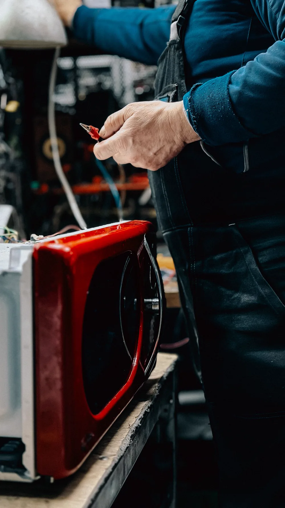 Técnico com o micro-ondas aberto na bancada, avaliando os componentes internos